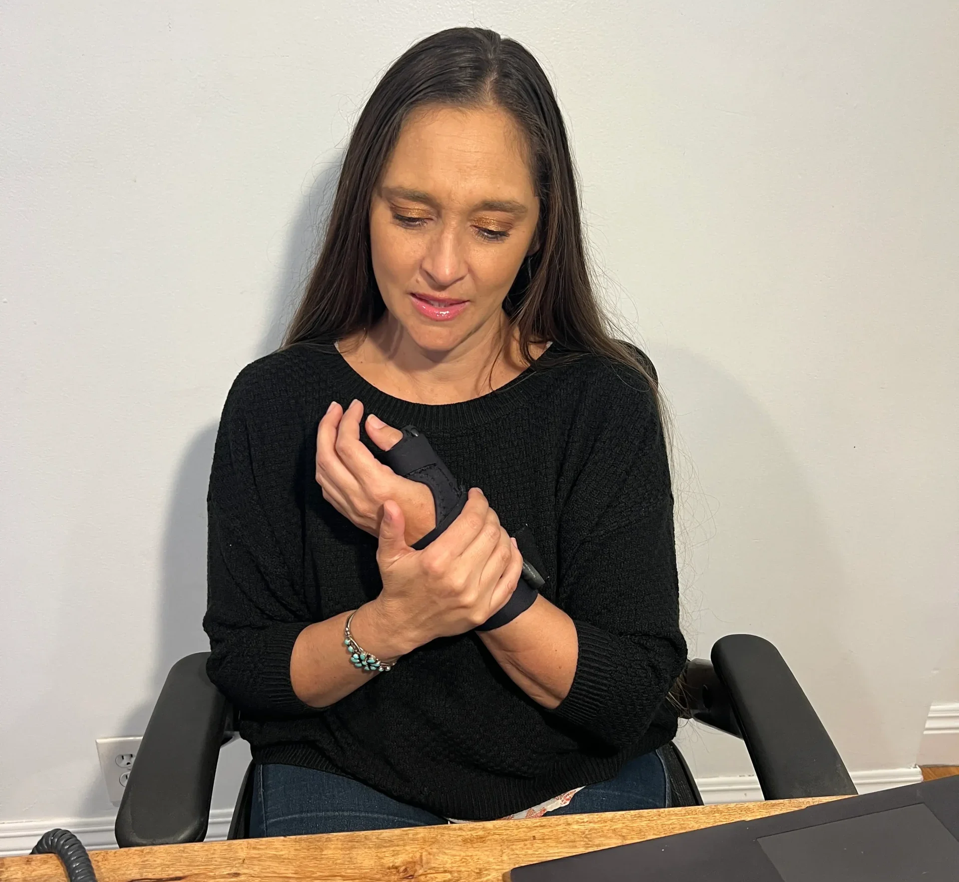 Employee wearing a wrist brace while working at a computer, illustrating workplace wrist pain or repetitive strain injury